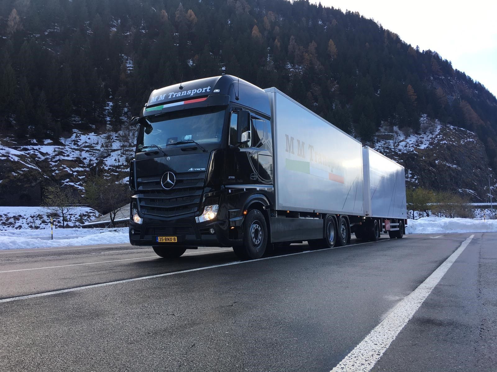 Black M M Transport Mercedes truck with trailer in the snowy Alps
