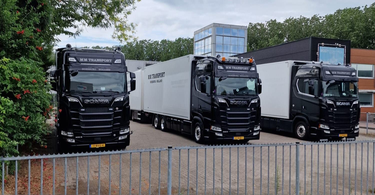 Three black M M Transport trucks side by side