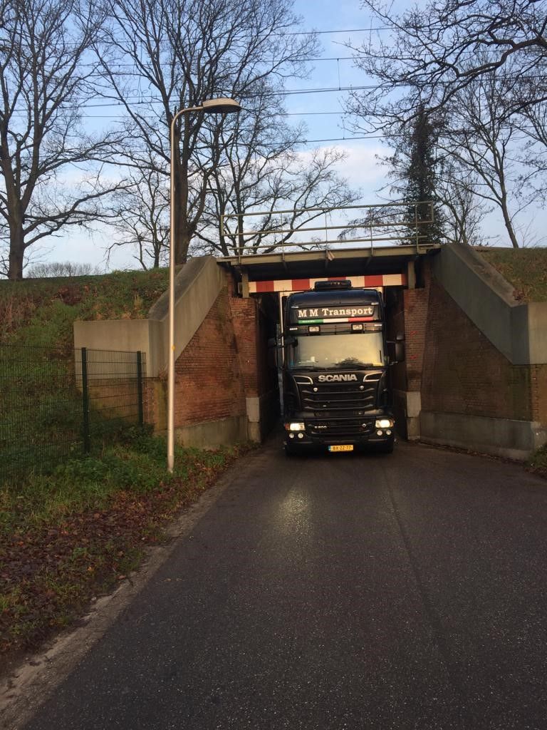 M M Transport truck driving under a narrow underpass